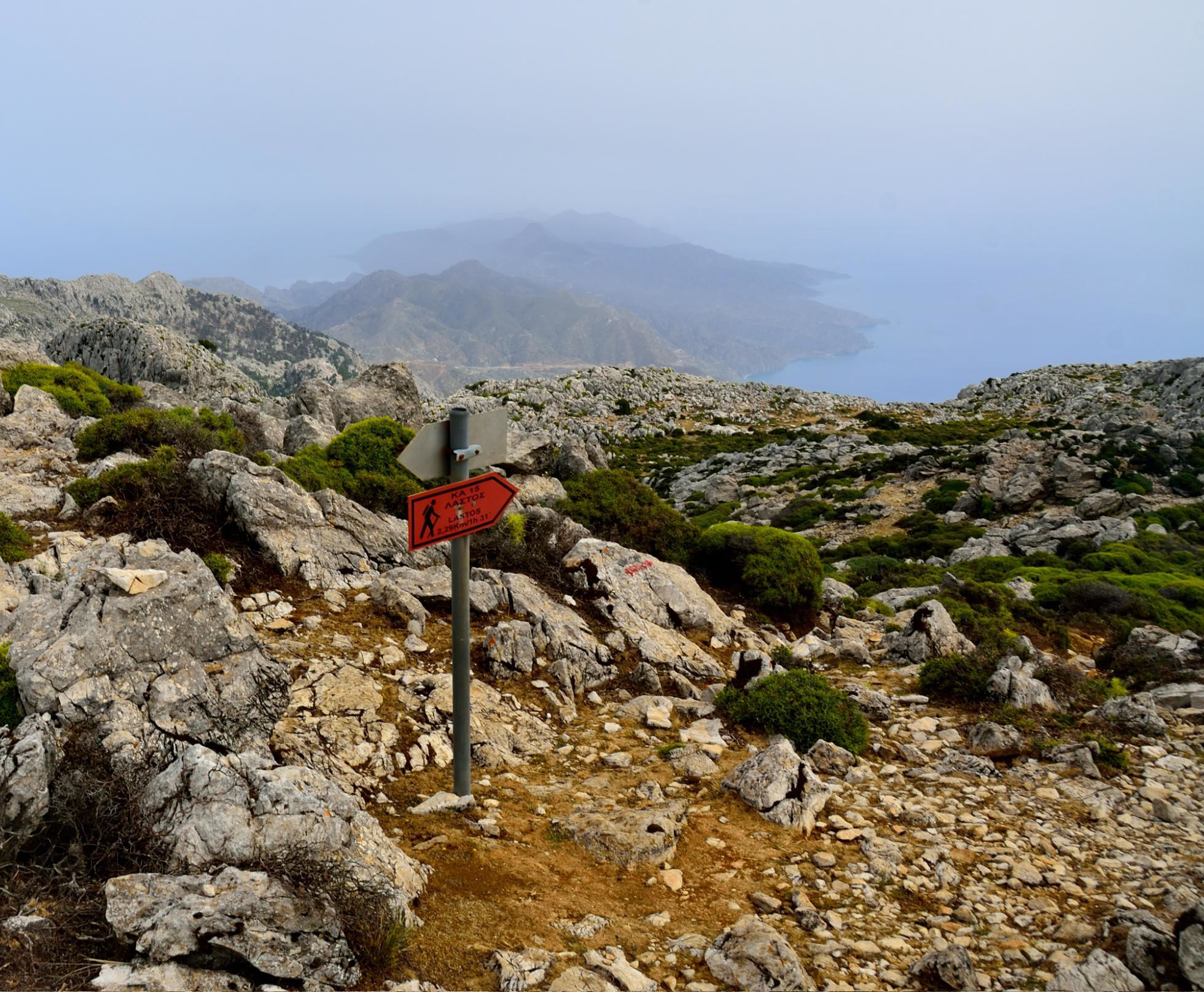 Turistický smerovník na planinu Lastos, v pozadí výhľady z vrcholu Kali Limni