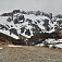 Horná časť lyžiarskeho strediska so zasneženou hradbou hôr
