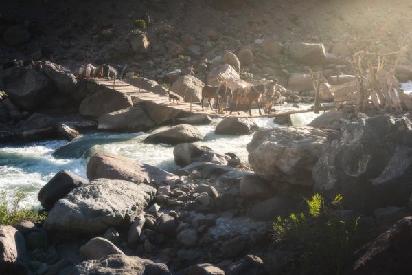 Skupina arrierov na koňoch prechádza ponad jednu z horských riek